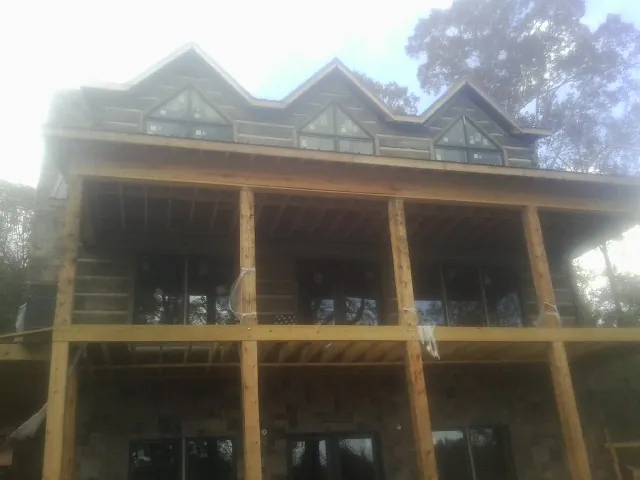 Dormers and porch framing on a large log home under construction — Roof Coating work by our crew in Orleans