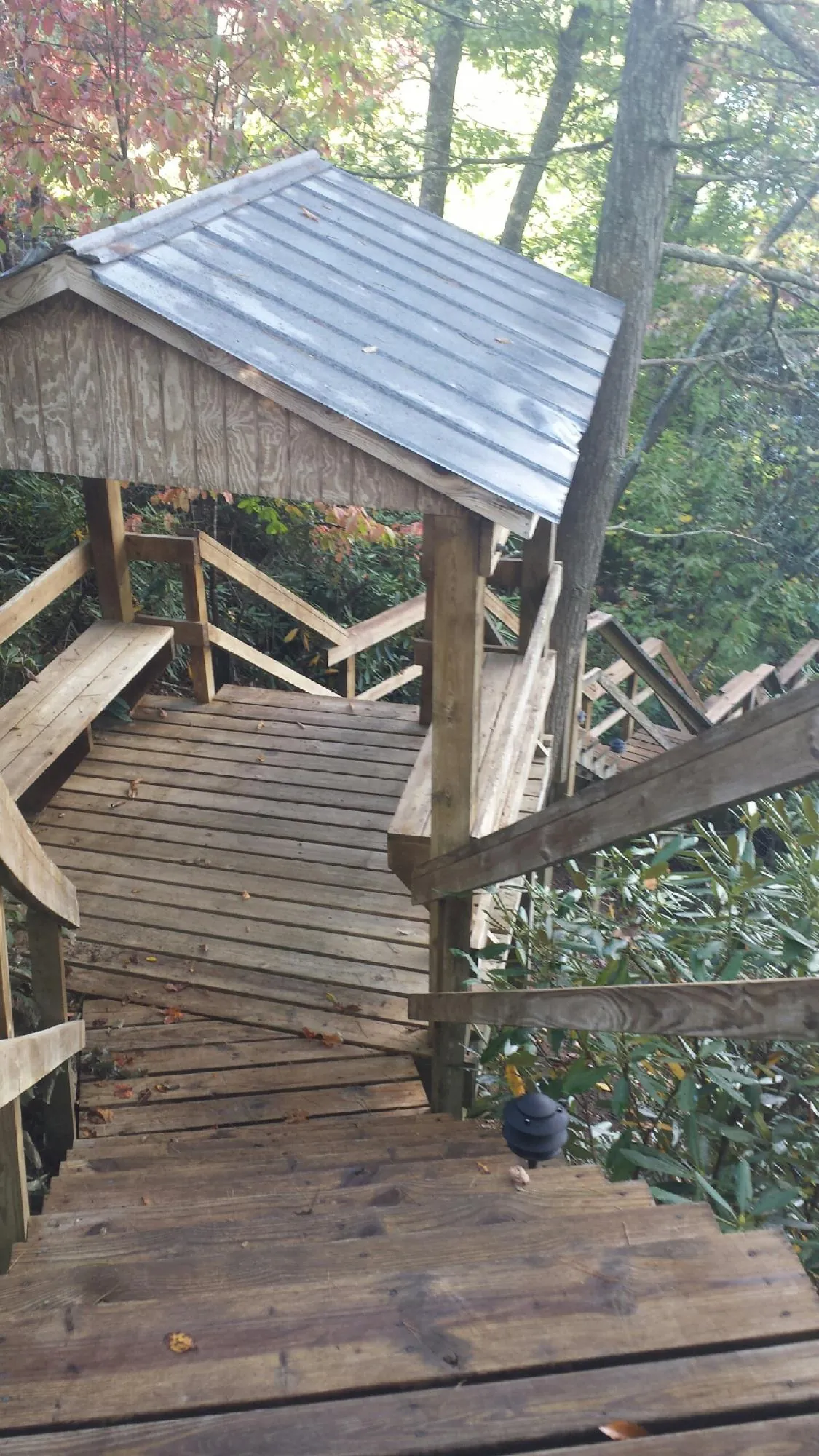 Metal roofed shelter over wooden steps on a wooded walkway — Skylight Repair & Installation work by our crew in Orleans